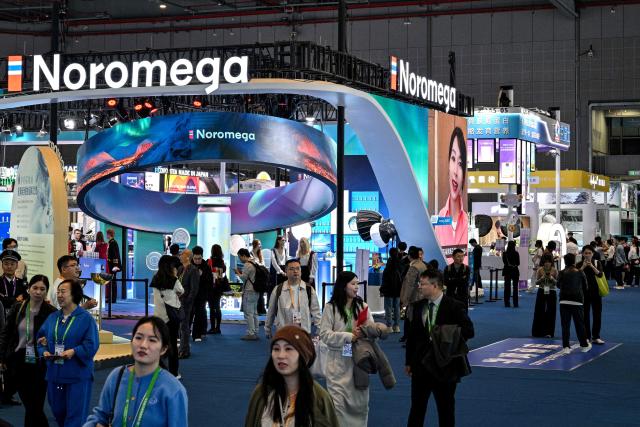 Visitors are seen next to the dietary supplements at the Noromega stall during the 8th China International Import Expo (CIIE) in Shanghai on November 6, 2025. (Photo by Hector RETAMAL / AFP)