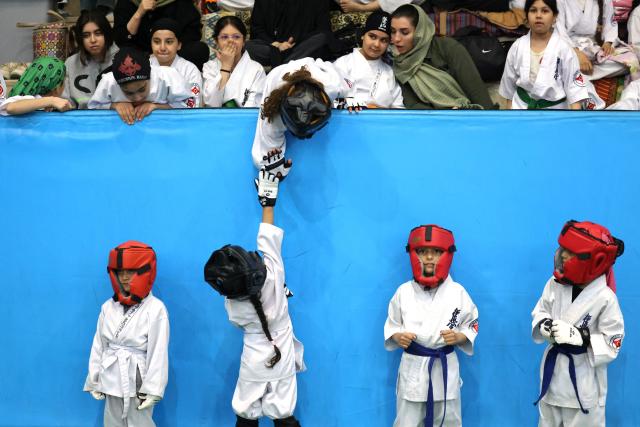 A young athlete reaches up to give a "high-five" during the women's karate competition, made-up of clubs and teams from around the Tehran province, in Tehran on November 6, 2025. Some 230 participants, including 5-year-old girls, took part in the competition, with team's deriving only from the Tehran province taking part. (Photo by ATTA KENARE / AFP)