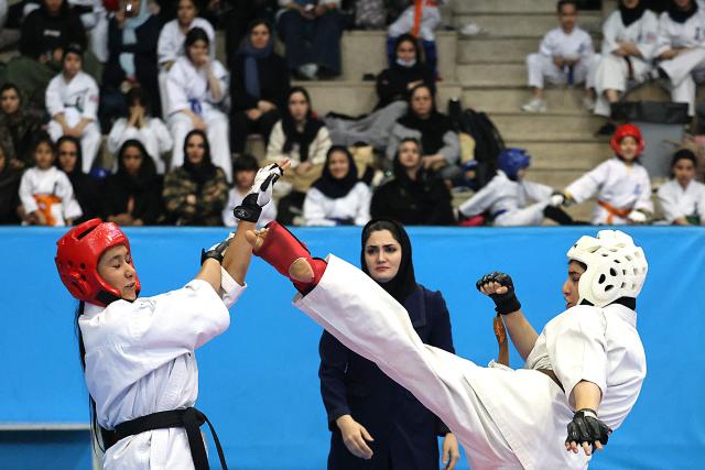 A referee adjudicate during an all women's karate competition made up of clubs and teams from around the Tehran province, in Tehran on November 6, 2025. Some 230 participants, including 5-year-old girls, took part in the competition, with team's deriving only from the Tehran province taking part. (Photo by ATTA KENARE / AFP)