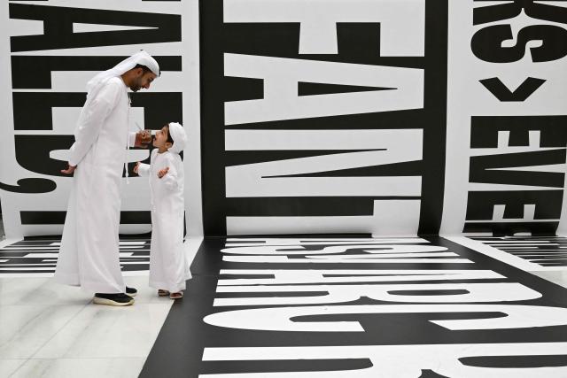 A man interacts with a boy while attending the Sharjah International Book Fair in the Gulf emirate of Sharjah, on November 6, 2025. (Photo by Giuseppe CACACE / AFP)