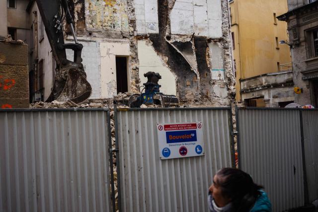 A woman walks past the construction site at 48, Rue de la République in Saint-Denis, North of Paris on November 6, 2025, where the RAID raid took place after the attacks of November 13, 2015. (Photo by Dimitar DILKOFF / AFP)