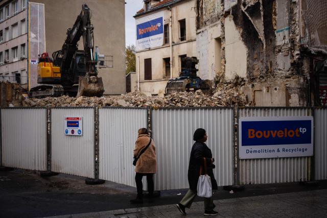People walk past the construction site at 48, Rue de la République in Saint-Denis, North of Paris on November 6, 2025, where the RAID raid took place after the attacks of November 13, 2015. (Photo by Dimitar DILKOFF / AFP)