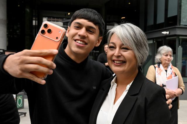 Chile's presidential candidate Jeannette Jara (L), of the Unidad por Chile coalition, poses for a selfie with a supporter after a meeting with Cooperatives of Chile, a national association founded in 2018 that represents and advocates for cooperative organizations across the country, in Santiago, on November 6, 2025. Chile will hold the presidential election on November 16. (Photo by RODRIGO ARANGUA / AFP)