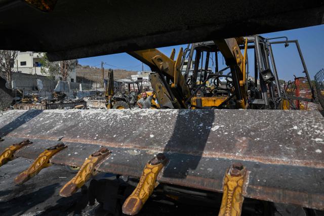 A man stands next to a burned construction vehicle at a site that was targeted in an Israeli strike in the southern Lebanese village of Ansaryeh on November 6, 2025. Israel struck Hezbollah targets in southern Lebanon on November 6, as the group rejected the prospect of direct political talks between the two countries and vowed to defend itself. (Photo by JOSEPH EID / AFP)