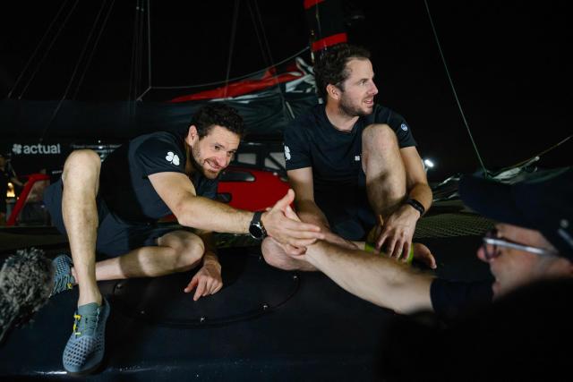 "Actual" Ultim multihull French skippers Julien Villion (C) and Anthony Marchand are congratulated by race director Francis Le Goff (R) after placing third in the Ultim class of 17th edition of the Transat Cafe L'Or, off the shores of Fort-de-France, in the French overseas island of Martinique on November 6, 2025. Four open classes take part in the race: IMOCA, Ocean Fifty, ULTIM and Class40. The Transat Cafe L'Or is a duo sailing race from Le Havre to Fort-de-France, in the French Caribbean island of Martinique. (Photo by Loic VENANCE / AFP)
