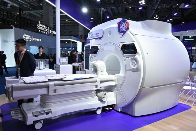 Visitors look at medical equipments in the GE HealthCare stand during the 8th China International Import Expo (CIIE) in Shanghai on November 7, 2025. (Photo by Hector RETAMAL / AFP)