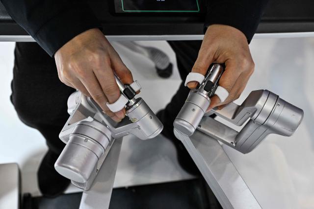 A visitor checks a robotic surgical equipment in the Ronovo stand during the 8th China International Import Expo (CIIE) in Shanghai on November 7, 2025. (Photo by Hector RETAMAL / AFP)