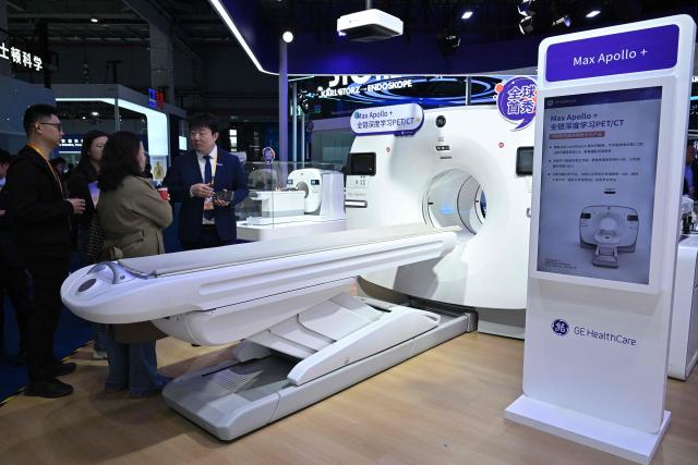 Visitors look at medical equipments in the GE HealthCare stand during the 8th China International Import Expo (CIIE) in Shanghai on November 7, 2025. (Photo by Hector RETAMAL / AFP)
