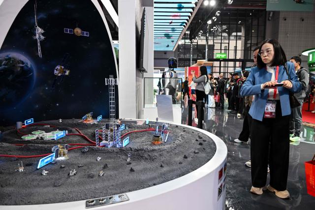 Visitors look at a scale model of the International Lunar Research Station at China's pavillion during the 8th International Import Expo (CIIE) in Shanghai on November 7, 2025. (Photo by Hector RETAMAL / AFP)