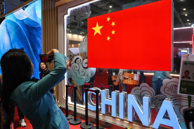 Visitors take pictures at China's pavillion during the 8th International Import Expo (CIIE) in Shanghai on November 7, 2025. (Photo by Hector RETAMAL / AFP)