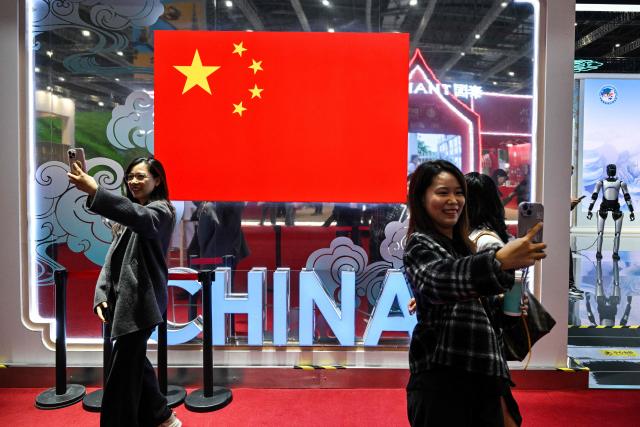 Visitors take pictures at China's pavillion during the 8th International Import Expo (CIIE) in Shanghai on November 7, 2025. (Photo by Hector RETAMAL / AFP)