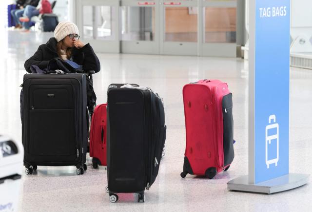 A traveler waits with her luggage at Newark Liberty International Airport in Newark, New Jersey, on November 7, 2025. Hundreds of flights were canceled across the United States on Friday after the Trump administration ordered reductions to ease strain on air traffic controllers who are working without pay amid congressional paralysis on funding the US budget. Forty airports were due to slow down, including the giant hubs in Atlanta, Newark, Denver, Chicago, Houston and Los Angeles. (Photo by TIMOTHY A. CLARY / AFP)