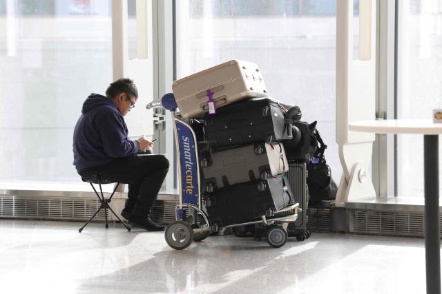 A traveler waits with his luggage at Newark Liberty International Airport in Newark, New Jersey, on November 7, 2025. Hundreds of flights were canceled across the United States on Friday after the Trump administration ordered reductions to ease strain on air traffic controllers who are working without pay amid congressional paralysis on funding the US budget. Forty airports were due to slow down, including the giant hubs in Atlanta, Newark, Denver, Chicago, Houston and Los Angeles. (Photo by TIMOTHY A. CLARY / AFP)