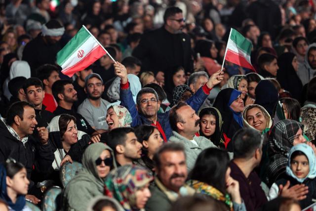 An Iranian man waves national flags during the unveiling of a statue depicting Sasanian king Shapur I capturing Roman emperor Valerian, at Enghelab (Revolution) Square in the capital Tehran on November 7, 2025. The event was the latest in a series of unveiling national symbols following Iran's recent 12-day war with Israel in June. The statue was modelled on an original stone engraving in southern Iran, symbolising Iranian triumph over foreign foes. (Photo by AFP)