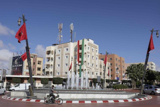 CORRECTION / A man rides past a roundabout adorned with Moroccan national flags in Laayoune, the main city of Moroccan-controlled Western Sahara, on November 7, 2025. The UN Security Council voted on October 31, 2025 in favor of a resolution backing Morocco's autonomy plan for Western Sahara as the "most feasible" solution for the disputed territory, triggering celebrations in Rabat but angering Algeria. (Photo by Abdel Majid BZIOUAT / AFP) / The erroneous mention[s] appearing in the metadata of this photo by Abdel Majid BZIOUAT has been modified in AFP systems in the following manner: [on November 7, 2025] instead of [on November 6, 2025]. Please immediately remove the erroneous mention[s] from all your online services and delete it (them) from your servers. If you have been authorized by AFP to distribute it (them) to third parties, please ensure that the same actions are carried out by them. Failure to promptly comply with these instructions will entail liability on your part for any continued or post notification usage. Therefore we thank you very much for all your attention and prompt action. We are sorry for the inconvenience this notification may cause and remain at your disposal for any further information you may require.