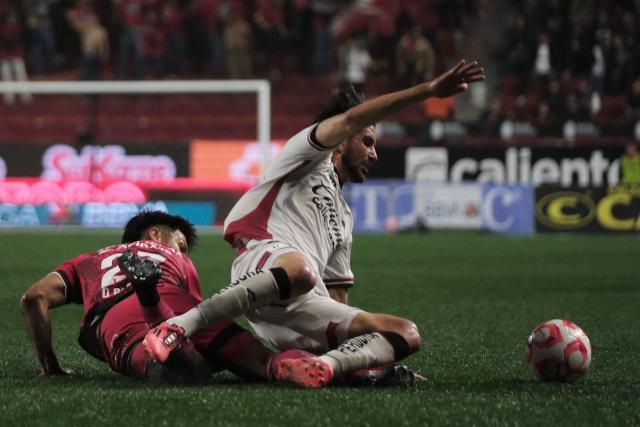 Tijuana's Argentine midfielder #27 Domingo Blanco and Atlas' defender #13 Gaddi Aguirre fight for the ball during the Liga MX Apertura football match between Tijuana and Atlas at Caliente Stadium in Tijuana, Mexico on November 7, 2025. (Photo by Guillermo Arias / AFP)
