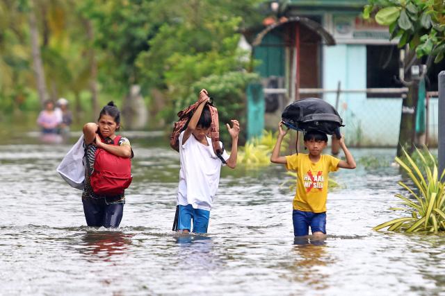 Residents evacuate from their flooded homes due to heavy rain brought by Typhoon Fung-wong in Remedios T. Romualdez, on the southern island of Mindanao on November 8, 2025. Rescue work was suspended and preemptive evacuations began on November 8 as Typhoon Fung-wong bore down on the Philippines, days after another storm killed at least 204 people. (Photo by Erwin MASCARINAS / AFP)