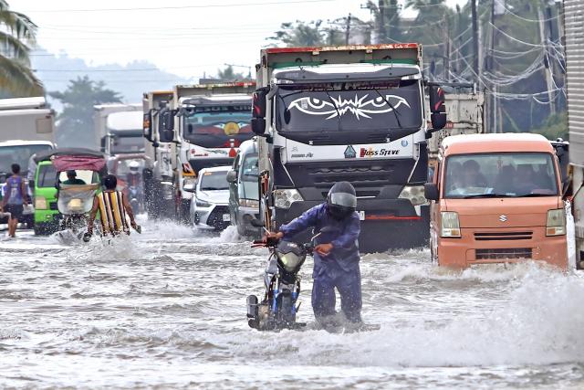 A motorist wades through a flooded highway due to heavy rain brought by Typhoon Fung-wong in Remedios T. Romualdez, on the southern island of Mindanao on November 8, 2025. Rescue work was suspended and preemptive evacuations began on November 8 as Typhoon Fung-wong bore down on the Philippines, days after another storm killed at least 204 people. (Photo by Erwin MASCARINAS / AFP)