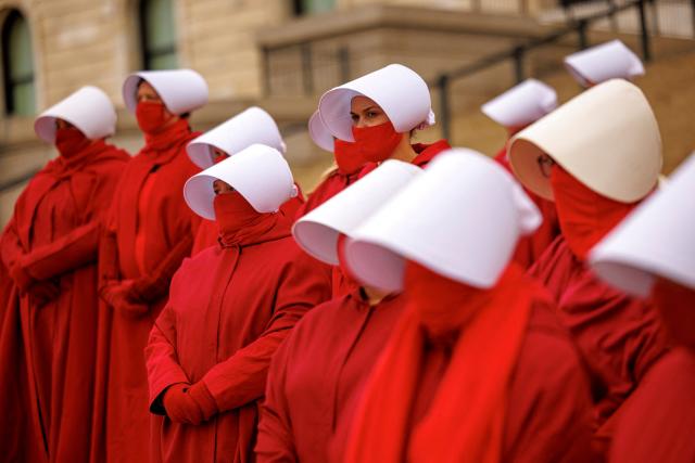Participants dressed in long red robes and white bonnet-style headpieces, resembling characters from The Handmaid’s Tale, take part in the Handmaids' National Day of Action outside the Minnesota State Capitol in Saint Paul, Minnesota, on November 8, 2025. (Photo by Kerem YUCEL / AFP)