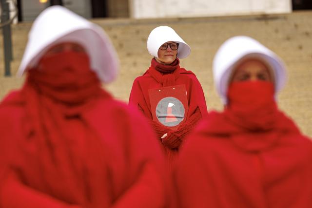 Participants dressed in long red robes and white bonnet-style headpieces, resembling characters from The Handmaid’s Tale, take part in the Handmaids' National Day of Action outside the Minnesota State Capitol in Saint Paul, Minnesota, on November 8, 2025. (Photo by Kerem YUCEL / AFP)