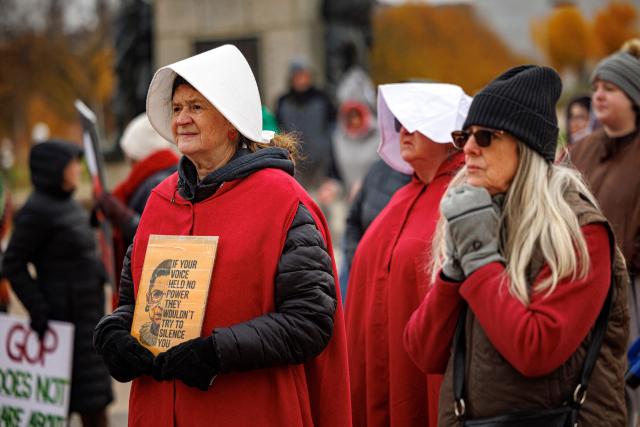 Participants dressed in long red robes and white bonnet-style headpieces, resembling characters from The Handmaid’s Tale, take part in the Handmaids' National Day of Action outside the Minnesota State Capitol in Saint Paul, Minnesota, on November 8, 2025. (Photo by Kerem YUCEL / AFP)