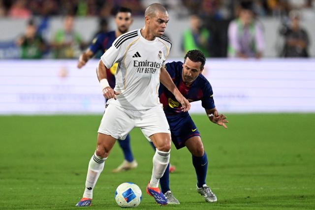 Real Madrid's Pepe and Barcelona's Ludovic Giuly fight for the ball during the exhibition friendly football match between Spain's Barcelona Legends and Real Madrid Legends at the Jorge "El Magico" Gonzalez Stadium in San Salvador on November 8, 2025. (Photo by Marvin RECINOS / AFP)