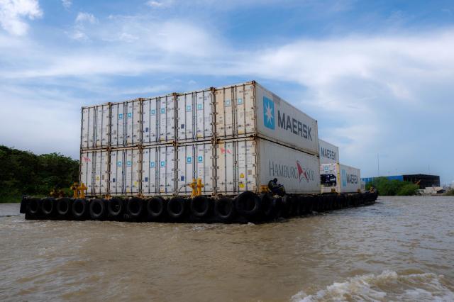 Boats transport containers in Puerto Antioquia in the Gulf of Uraba, Antioquia department, Colombia on November 8, 2025. France's Foreign Affairs Minister Jean-Noel Barrot travelled to the troubled Gulf of Uraba to visit a huge port under construction, which is one of the largest French private investment projects in Colombia, according to the diplomatic delegation. (Photo by Luis ACOSTA / AFP)