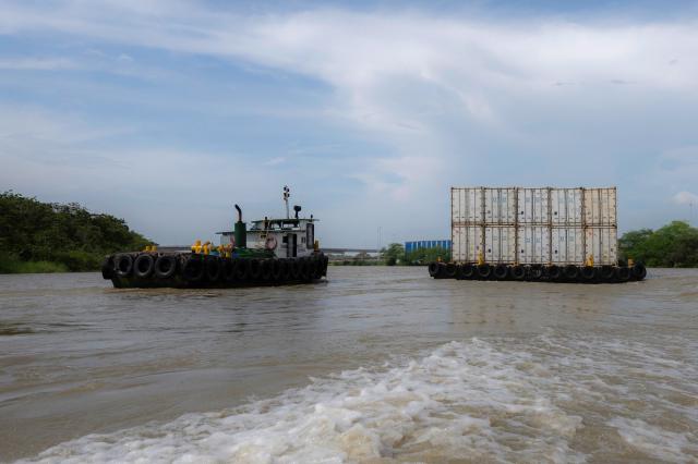 Boats transport containers in Puerto Antioquia in the Gulf of Uraba, Antioquia department, Colombia on November 8, 2025. France's Foreign Affairs Minister Jean-Noel Barrot travelled to the troubled Gulf of Uraba to visit a huge port under construction, which is one of the largest French private investment projects in Colombia, according to the diplomatic delegation. (Photo by Luis ACOSTA / AFP)