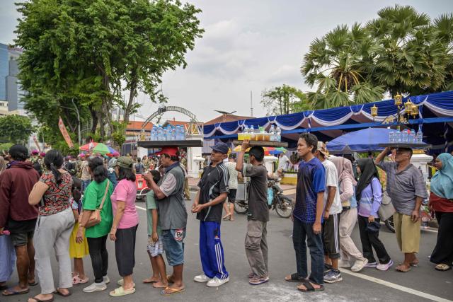 People queue to receive gifts from the Indonesian marines during the Indonesian Marine Fair, marking the 80th anniversary of the Indonesian Marine Corps, along a road in Surabaya on November 9, 2025. (Photo by JUNI KRISWANTO / AFP)