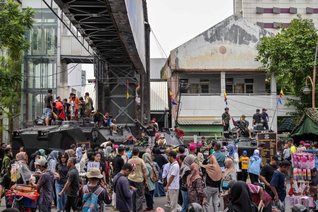 People take pictures with military vehicles during the Indonesian Marine Fair, marking the 80th anniversary of the Indonesian Marine Corps, along a road in Surabaya on November 9, 2025. (Photo by JUNI KRISWANTO / AFP)