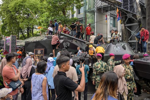 People take pictures with military vehicles during the Indonesian Marine Fair, marking the 80th anniversary of the Indonesian Marine Corps, along a road in Surabaya on November 9, 2025. (Photo by JUNI KRISWANTO / AFP)