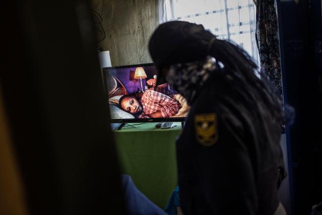 (FILES) A TV screen shows the picture of a woman lying in bed as a South African policewoman enters a room at the Nguni Hostels in Vosloorus, on July 27, 2021 during a joint operation between the South Africa Police Service (SAPS) and the South Africa National Defence Forces (SANDF). The trial of Duduzile Zuma-Sambudla, daughter of South Africa's former president Jacob Zuma, accused of inciting 2021 riots that left more than 350 people dead, was set by the Durban High Court to start November 10, 2025.
Duduzile Zuma-Sambudla, 42, is among several people charged with inciting terrorism and public violence via posts on social media after Zuma was sent to prison in July 2021 for refusing to testify in corruption proceedings against him.
The explosion of rioting and looting that followed was the deadliest unrest in South Africa since the fall of the white-minority government in 1994. 
Zuma-Sambudla denies the charges and claims the case is politically motivated. (Photo by MARCO LONGARI / AFP)