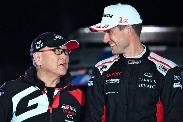 Race winner Sebastien Ogier (R) of France chats with Toyota Gazoo Racing chairman Akio Toyoda (L) during the podium ceremony of the Rally Japan, the 13th round of the FIA World Rally Championships, in Toyota city, Aichi prefecture on November 9, 2025. (Photo by Toshifumi KITAMURA / AFP)
