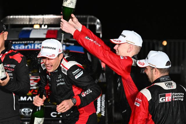 Sami Pajari of Finland (C) pours sake onto Sebastien Ogier of France (L) during the podium ceremony of the Rally Japan, the 13th round of the FIA World Rally Championships, in Toyota city, Aichi prefecture on November 9, 2025. (Photo by Toshifumi KITAMURA / AFP)