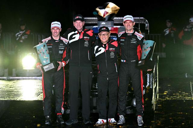Rally Japan winners Sebastien Ogier (R) and his co-driver Vincent Landais (L) of France pose with Toyota Gazoo Racing chairman Akio Toyoda (2nd R) and team manager Juha Kankkunen of Finland (2nd L) during the podium ceremony of the Rally Japan, the 13th round of the FIA World Rally Championships, in Toyota city, Aichi prefecture on November 9, 2025. (Photo by Toshifumi KITAMURA / AFP)