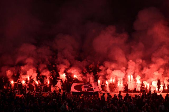 Supporters hold smoke flares as they cheer during the French L1 football match between Olympique Lyonnais (OL) and Paris Saint-Germain (PSG) at the Groupama Stadium in Decines-Charpieu, central-eastern France, on November 9, 2025. (Photo by Jean-Philippe KSIAZEK / AFP)