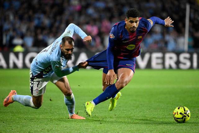 Celta Vigo's Spanish forward #07 Borja Iglesias and Barcelona's Uruguayan defender #04 Ronald Federico Araujo da Silva fight for the ball during the Spanish league football match between RC Celta de Vigo and FC Barcelona at Balaidos Stadium in Vigo on November 9, 2025. (Photo by Miguel RIOPA / AFP)