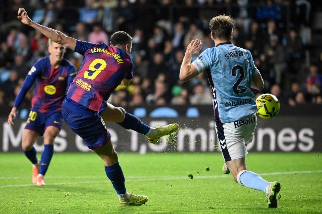 Barcelona's Polish forward #09 Robert Lewandowski shoots past Celta Vigo's Swedish defender #02 Carl Starfelt during the Spanish league football match between RC Celta de Vigo and FC Barcelona at Balaidos Stadium in Vigo on November 9, 2025. (Photo by Miguel RIOPA / AFP)