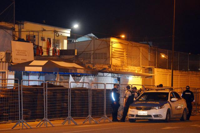 Police officers stand guard at the entrance of the prison after an armed riot that left four dead and dozens more injured in Machala, Ecuador on November 9, 2025. At least 27 prisoners were found dead from asphyxiation on Sunday afternoon in a prison in southwestern Ecuador, hours after police contained an armed riot that left four dead and dozens injured during the early hours of the morning. (Photo by Luis SUAREZ / AFP)