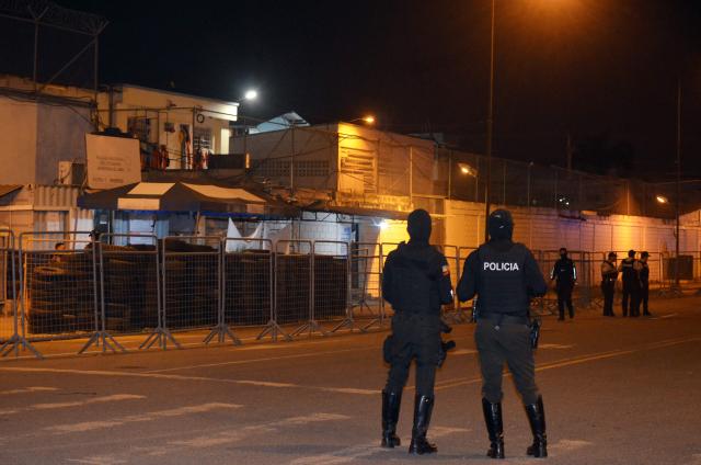 Police officers stand guard at the entrance of the prison after an armed riot that left four dead and dozens more injured in Machala, Ecuador on November 9, 2025. At least 27 prisoners were found dead from asphyxiation on Sunday afternoon in a prison in southwestern Ecuador, hours after police contained an armed riot that left four dead and dozens injured during the early hours of the morning. (Photo by Luis SUAREZ / AFP)