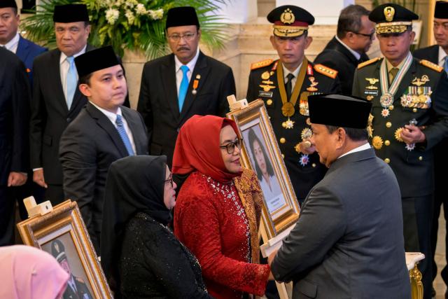 Indonesia's President Prabowo Subianto (R) congratulates the family of the late Marsinah, a female labour activist who was murdered during former President Suharto's leadership, during a ceremony held to mark the National Heroes Day at the State Palace in Jakarta on November 10, 2025. Indonesia added former president Suharto to a list of national heroes during a ceremony on November 10, despite objections from activists and academics over the deceased military dictator's human rights record. (Photo by BAY ISMOYO / AFP)