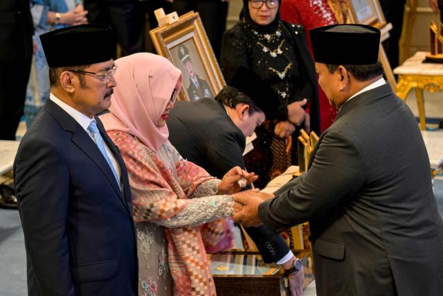 Indonesia's President Prabowo Subianto (R) congratulates the children of former president Suharto, Bambang Trihatmodjo (L) and Siti Hardijanti Rukmana (C), during a ceremony held to mark the National Heroes Day at the State Palace in Jakarta on November 10, 2025. Indonesia added former president Suharto to a list of national heroes during a ceremony on November 10, despite objections from activists and academics over the deceased military dictator's human rights record. (Photo by BAY ISMOYO / AFP)