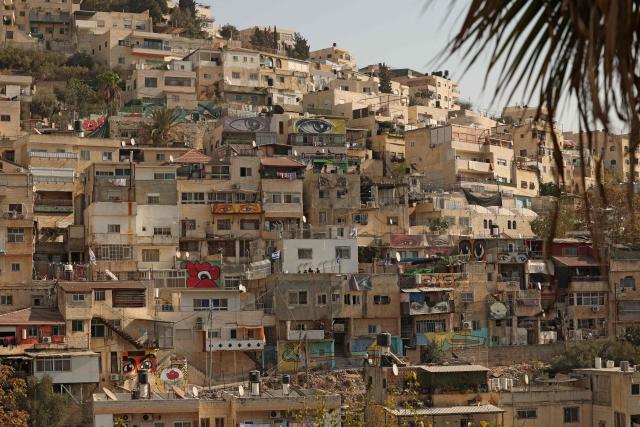 TOPSHOT - Israeli settlers place the Israeli flags on the roof of the Shweiki family house, after the Palestinian family was evicted by police from the house they lived in for decades, in east Jerusalem predominantly Arab neighbourhood of Silwan, on November 10, 2025. The eviction comes amid a decades-long legal battle between hundreds of Palestinian residents and an Israeli nonprofit, which claims the land under a 1970s law allowing Jews to reclaim property in East Jerusalem - rights not extended to Palestinians who were forced to abandon property in the cities. (Photo by AHMAD GHARABLI / AFP)
