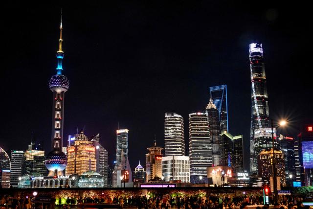People walk along a street near the Lujiazui financial district in Shanghai on November 10, 2025. (Photo by Hector RETAMAL / AFP)
