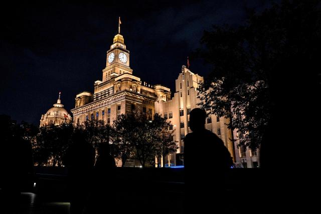 A man walks on the Bund promenade along the Huangpu river in Huangpu district in Shanghai on November 10, 2025. (Photo by Hector RETAMAL / AFP)