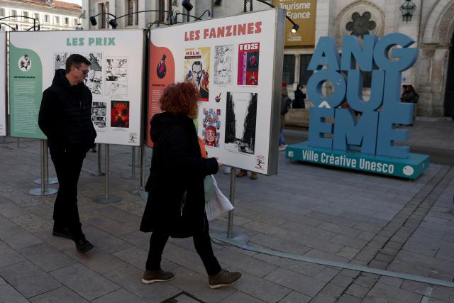 (FILES) Visitors look at placards as part of an exhibition during the 52nd Angouleme International Comics Festival in Angouleme, on January 30, 2025. The Angouleme International Comics Festival, one of the most famous in the world, is in "mortal danger", warned twenty Grand Prix winners, including Anouk Ricard, Lewis Trondheim, Jacques Tardi and Riad Sattouf, in the French newspaper L'Humanite on November 10, 2025, as calls to boycott the event multiply. (Photo by ROMAIN PERROCHEAU / AFP)