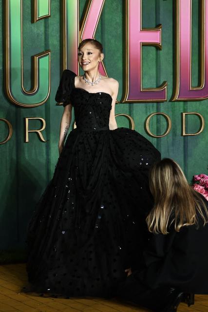 US actor Ariana Grande has her dress altered as she poses on the red carpet upon arrival for the European premiere of the film "Wicked: For Good" in central London on November 10, 2025. (Photo by HENRY NICHOLLS / AFP)