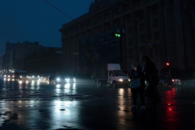 Pedestrians stand on a street without lighting in Kharkiv on November 10, 2025, following recent Russian missile and drone attacks on Ukrainian energy infrastructure, amid the Russian invasion of Ukraine. Russia has targeted the power and heating grid throughout its almost four-year invasion, destroying a large part of the key civilian infrastructure. (Photo by Ivan SAMOILOV / AFP)