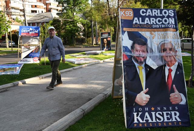 A man walks past electoral advertising posters in Santiago on November 10, 2025. Chile will hold presidential election on November 16. (Photo by RODRIGO ARANGUA / AFP)
