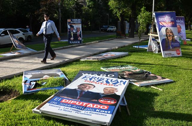 A man walks past electoral advertising posters in Santiago on November 10, 2025. Chile will hold presidential election on November 16. (Photo by RODRIGO ARANGUA / AFP)